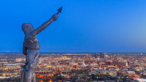 The Vulcan statue high above the nighttime cityscape in Birmingham, Alabama