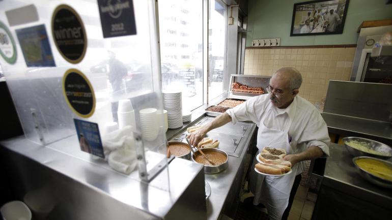 Lafayette Coney Island 餐厅的一名员工正在准备热狗 Lafayette Coney Island 餐厅的一名员工正在准备热狗