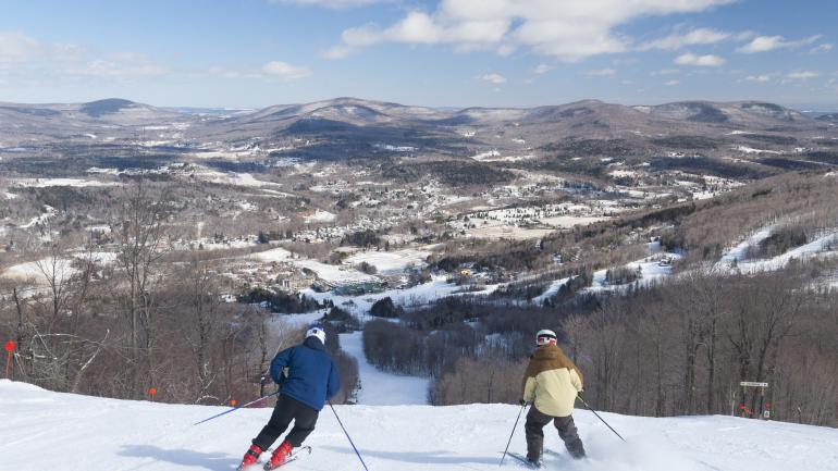 在温德姆山度假村眺望山谷美景和向下冲刺的滑雪者