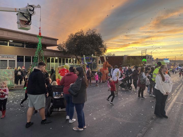 在亚利桑那州金曼市中心的 Very Merry Street of Lights 街道上欣赏节日灯饰与人造雪景的游客