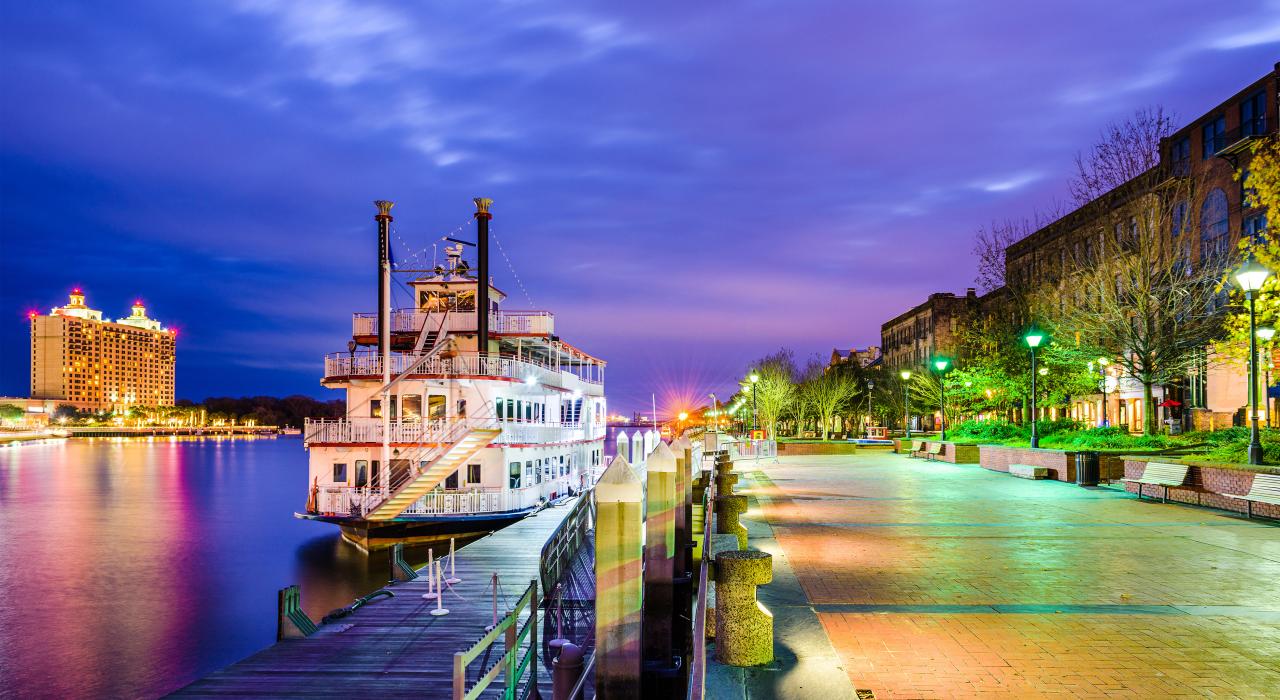 河船停靠在 River Street 街旁，街上精品店、酒馆和酒店林立