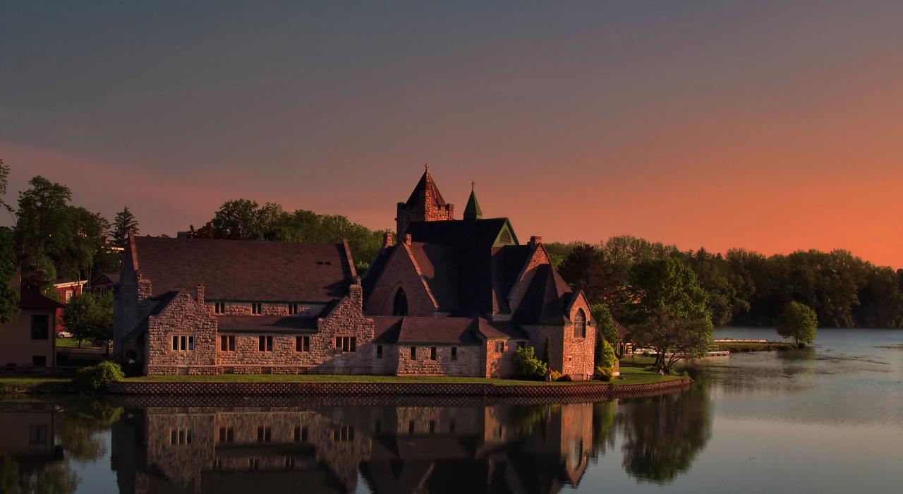 红铜色天空下塞内卡湖畔的一座教堂