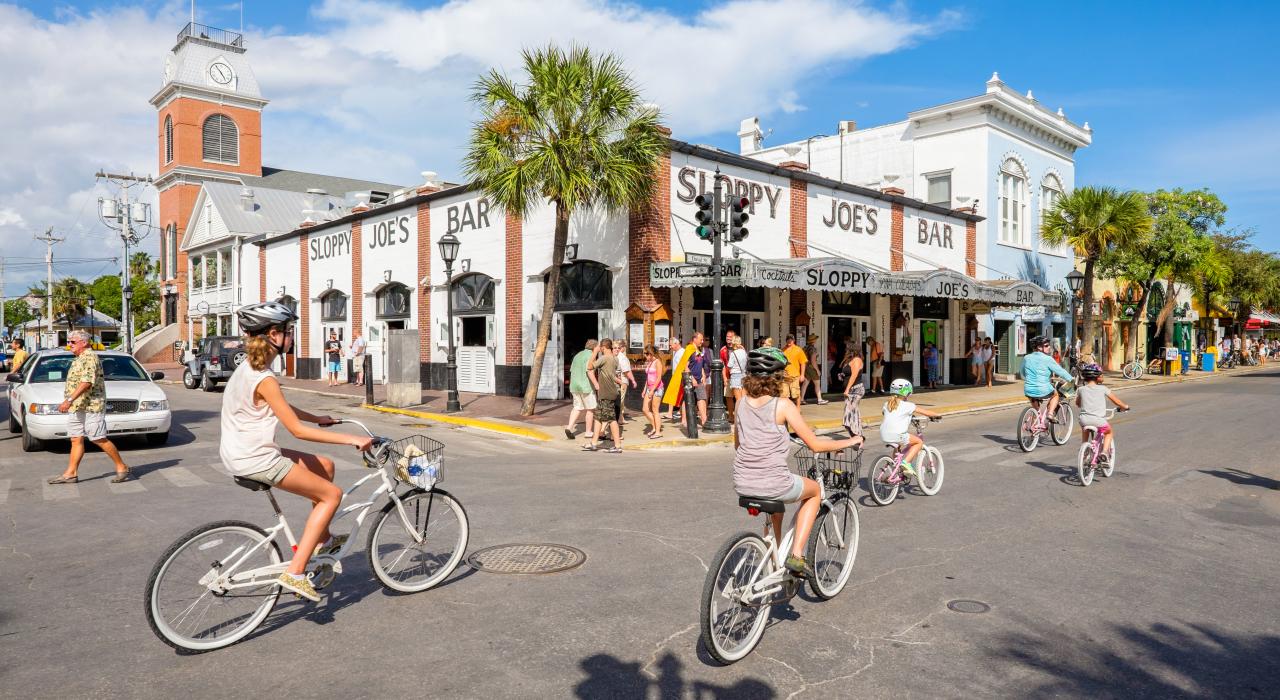骑自行车经过佛罗里达州基韦斯特的 Sloppy Joe's Bar 酒吧