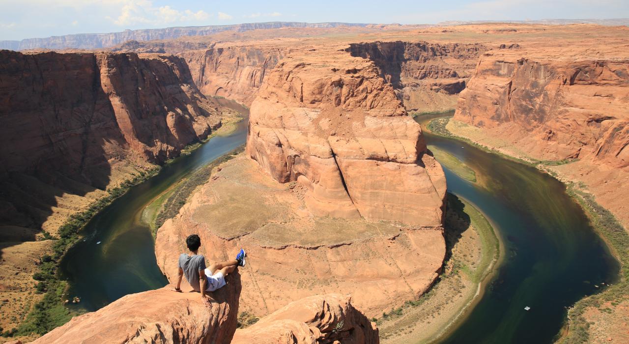 一名男子坐在悬崖观赏马蹄湾之景