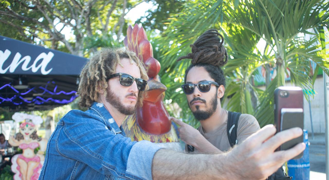 Xperimento 乐队的成员在迈阿密小哈瓦那社区的公鸡雕塑前自拍