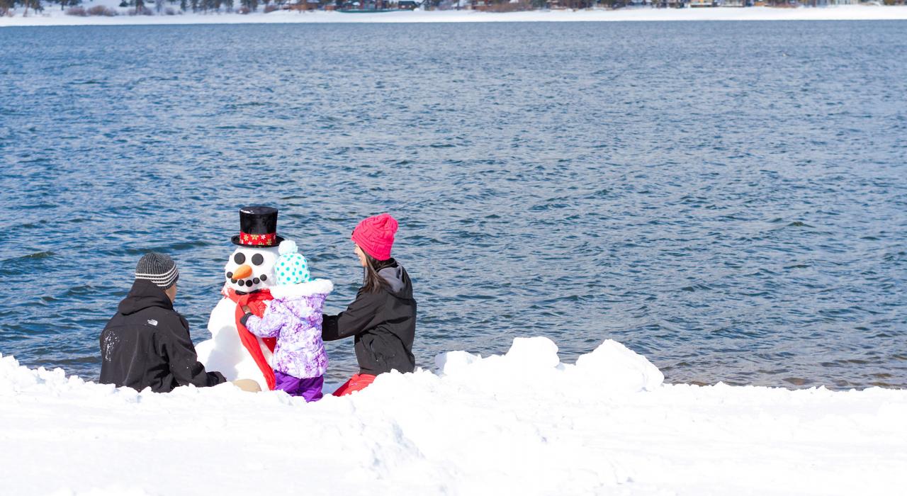 一家人在冬天的湖边堆雪人