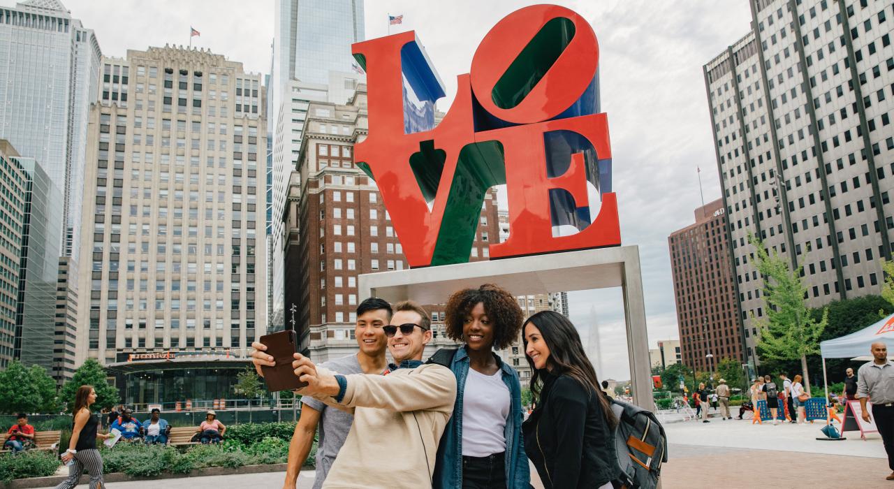 一群人在宾夕法尼亚州费城市中心附近的标志性“LOVE”雕塑前自拍