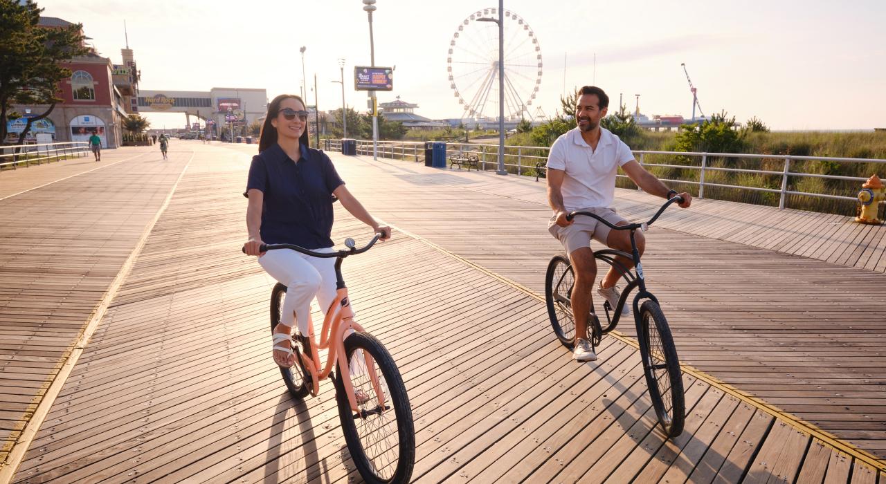 在钢铁码头游乐园 (Steel Pier amusement park) 附近的木板道上骑行