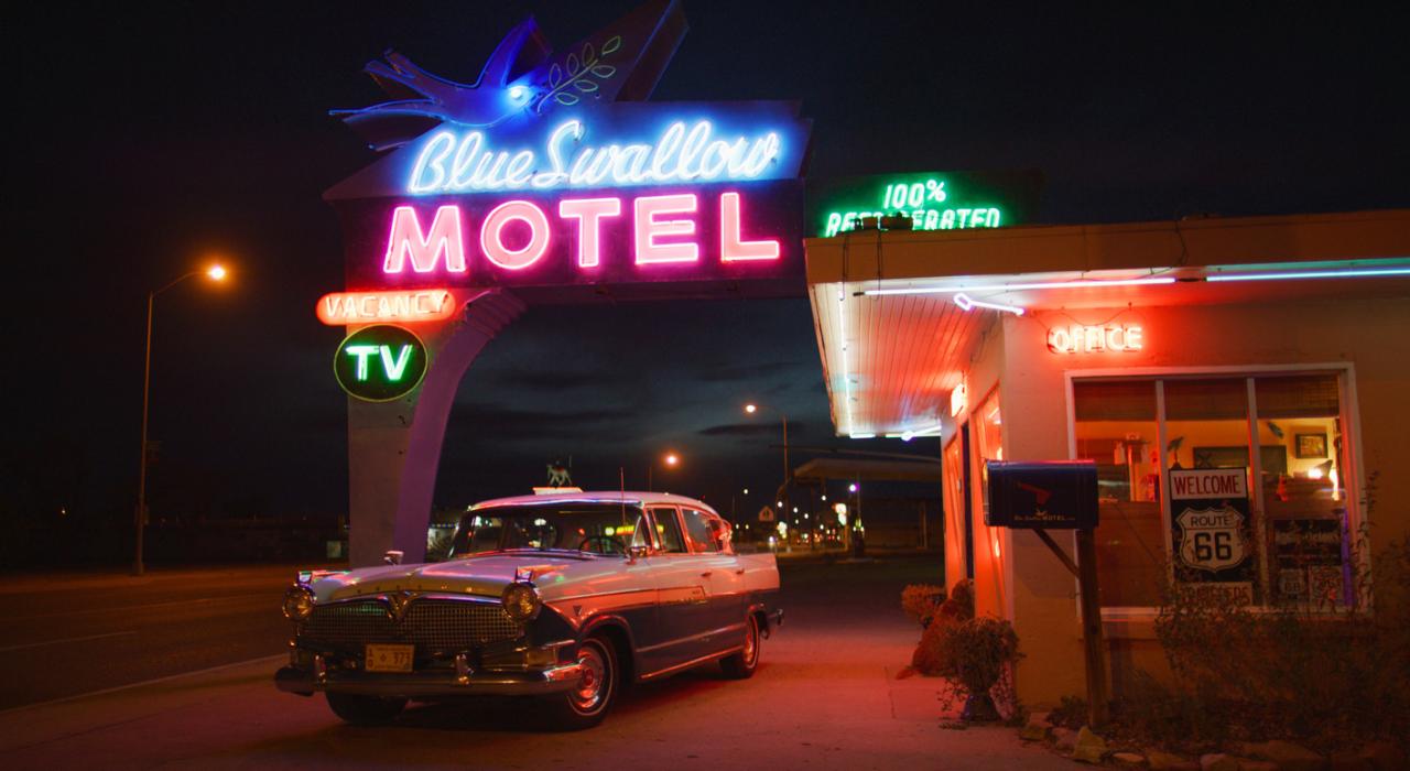 新墨西哥州图克姆卡里的 Blue Swallow Motel 汽车旅馆外有一辆老式汽车和标示旅馆名称的霓虹灯
