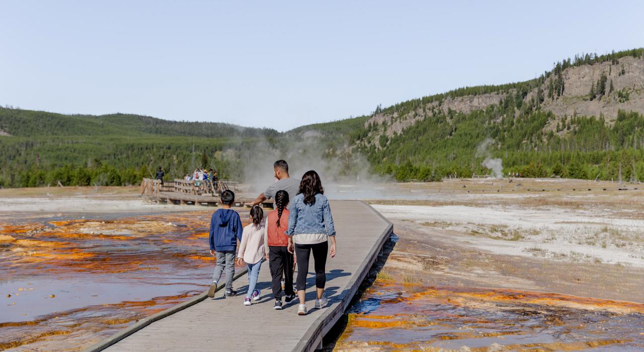 一家人在黄石国家公园的中途间歇泉盆地步道上散步