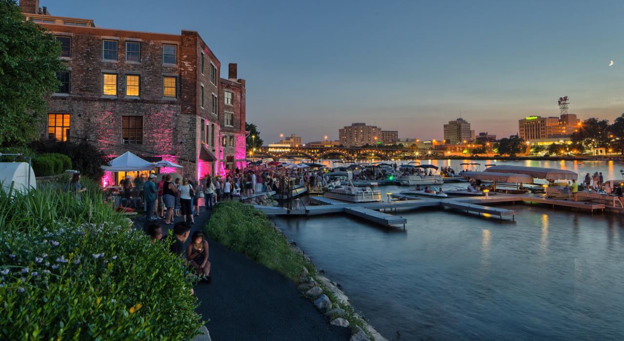 游客在伊利诺伊州罗克福德 Prairie Street Brewing Company 酿酒厂附近欣赏暮色下的美丽河景