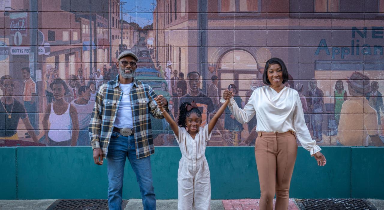 在描绘朗兹县 (Lowndes County) 悠久历史的鲶鱼小巷壁画 (Catfish Alley Mural) 前拍照留念