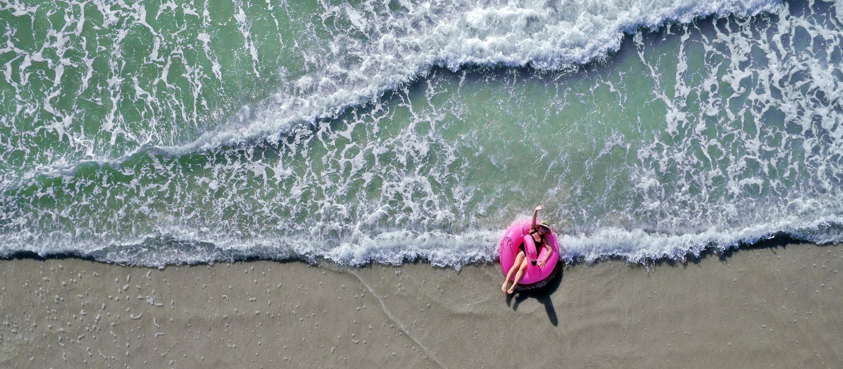 躺在火烈鸟漂筏上漂浮冲浪，在佛罗里达海滩上度过完美的一天